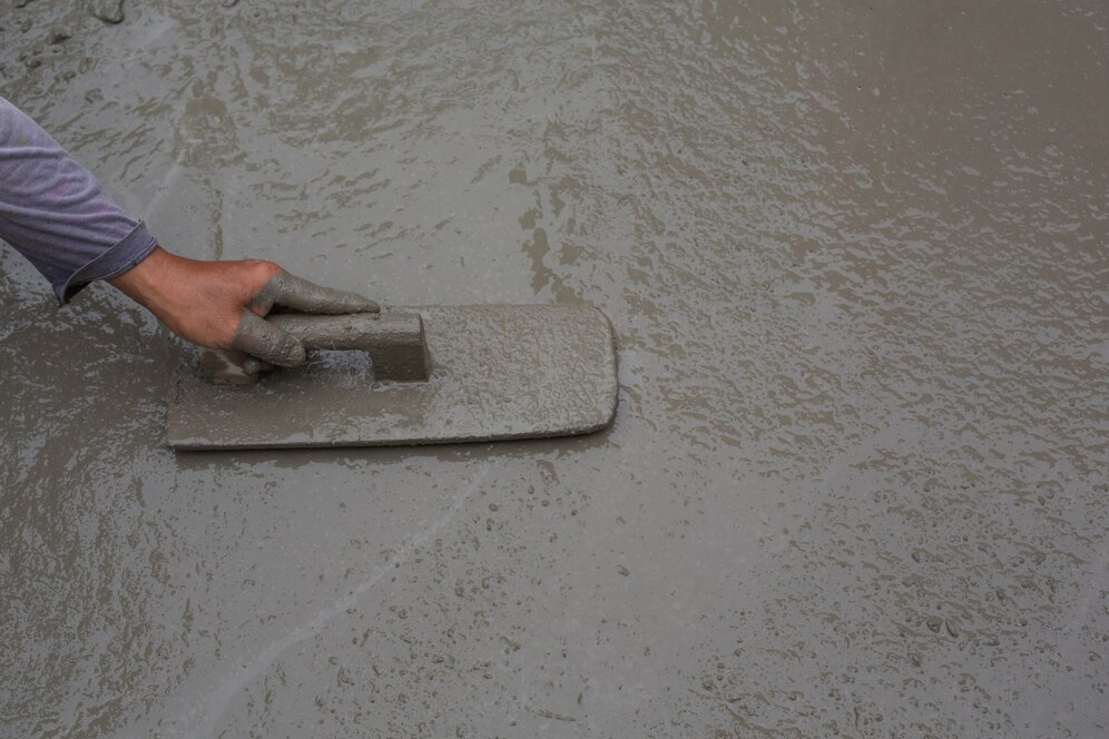 Worker smoothing wet cement — foundation preparation